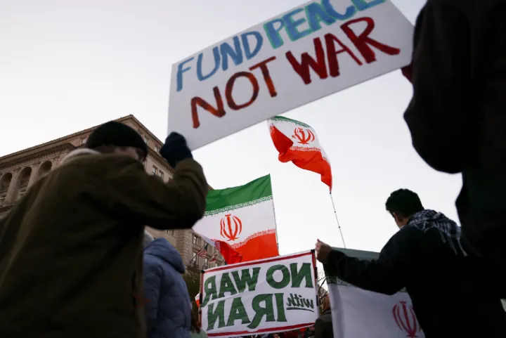 Manifestantes con pancartas contra la guerra y banderas de Irán